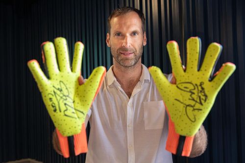 Petr Čech drží fotbalové golmanské rukavice s autogramy