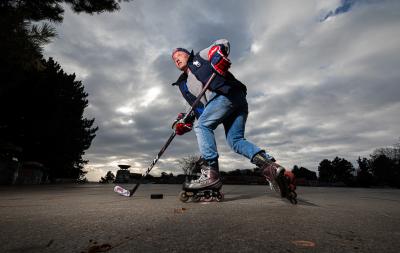 Mikael Pančák v inline bruslích s hokejkou a rukavicemi se projíždí v Praze u kyvadla