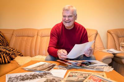 Vladimír Vůjtek sedí na gauči a prohlíží si staré fotografie a noviny