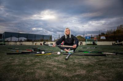 Kateřina Laciná sedí na hřišti a drží hokejku na pozemní hokej, má vedle sebe další hokejky