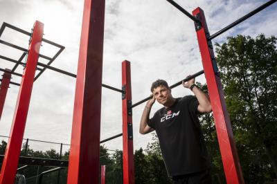 Petr Sýkora stojí u workoutového hřiště venku před stromy