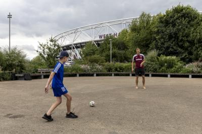 Tomáš Souček hraje fotbal s dětmi na písku před stadionem West Ham United.