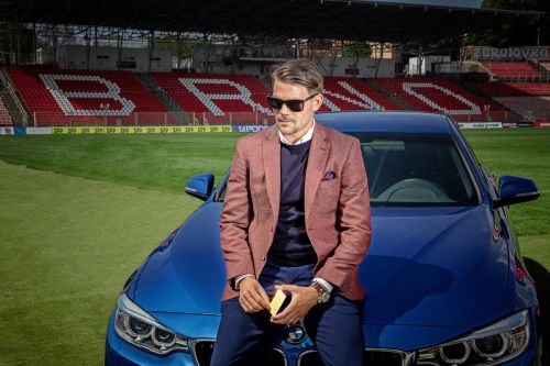 Luboš Kalouda opřený o auto na fotbalovém stadionu