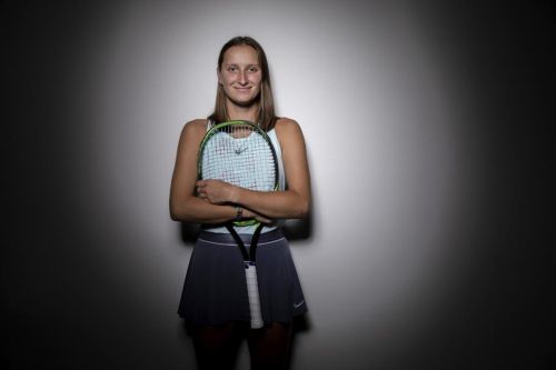 Markéta Vondroušová opřená o zeď s raketou v ruce.