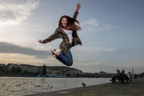 Martina Bravencová ve výskoku do vzduchu na pozadí plynoucí řeky.