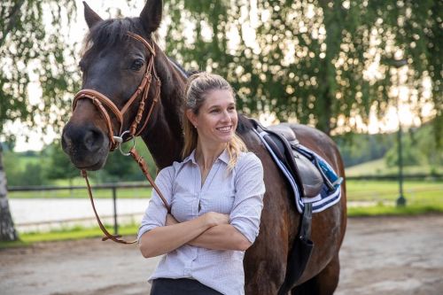 Michaela Kloudová se opírá o koně v přírodě