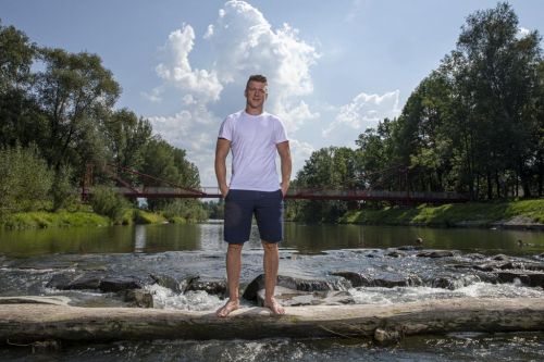 Ondřej Palát stojí uprostřed tekoucího potoka v přírodě.