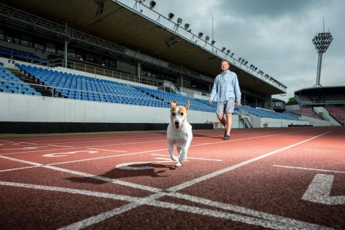 Tomáš Dvořák se svým psem běžícím po atletickém stadionu.