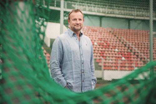 Tomáš Dvořák na atletickém stadionu pozuje u sítě.